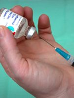 A hand holding a medical needle and the influenza vaccine.