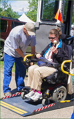 A woman in a wheelchair is lowered from an accessible van.